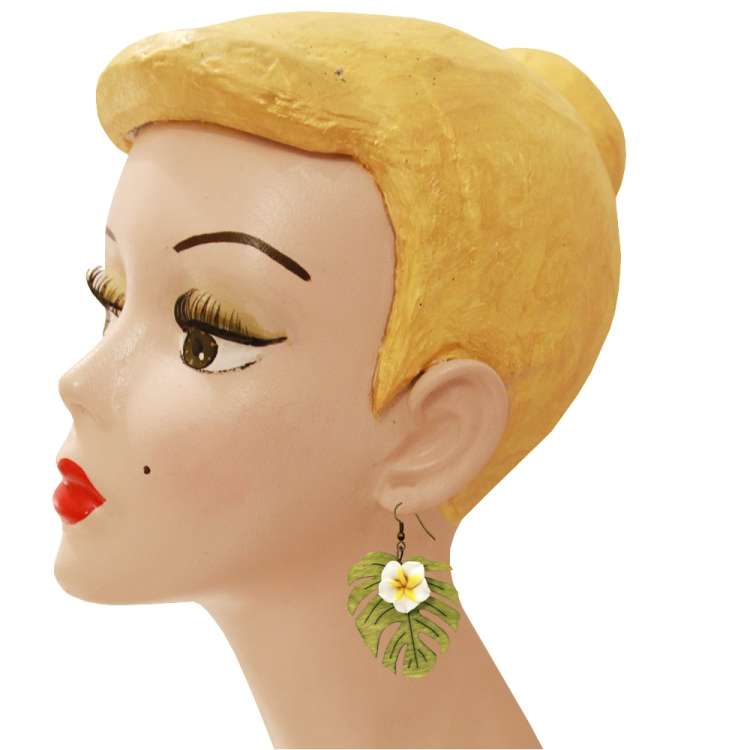 Kopf mit weißer Frangipani-Blüte und Monstera-Blatt-Ohrringen